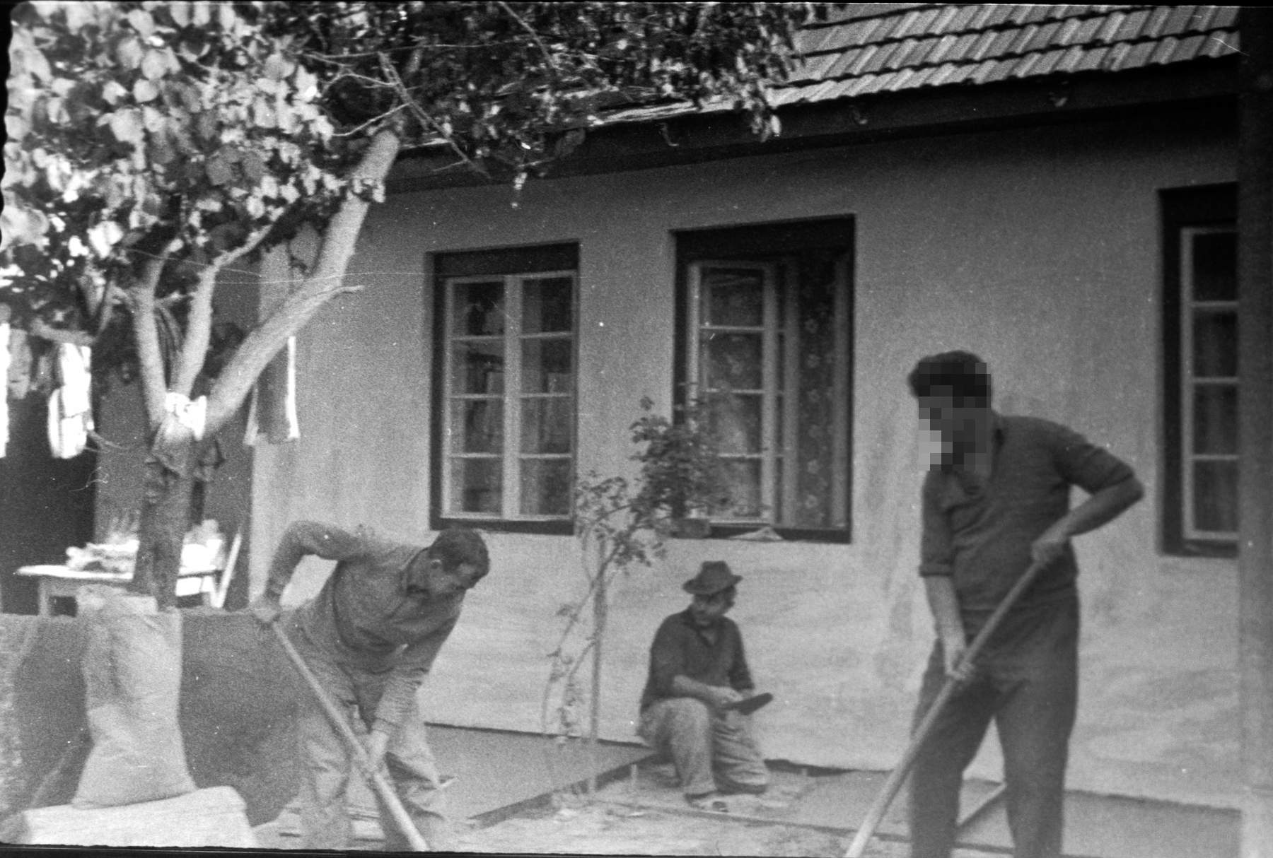 Dad with the masons, mixing cement with shovels. The guy is sitting where the yard tap will be.